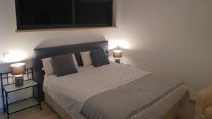 Une chambre à coucher avec un lit, deux lampes de chevet, une fenêtre et une petite table.