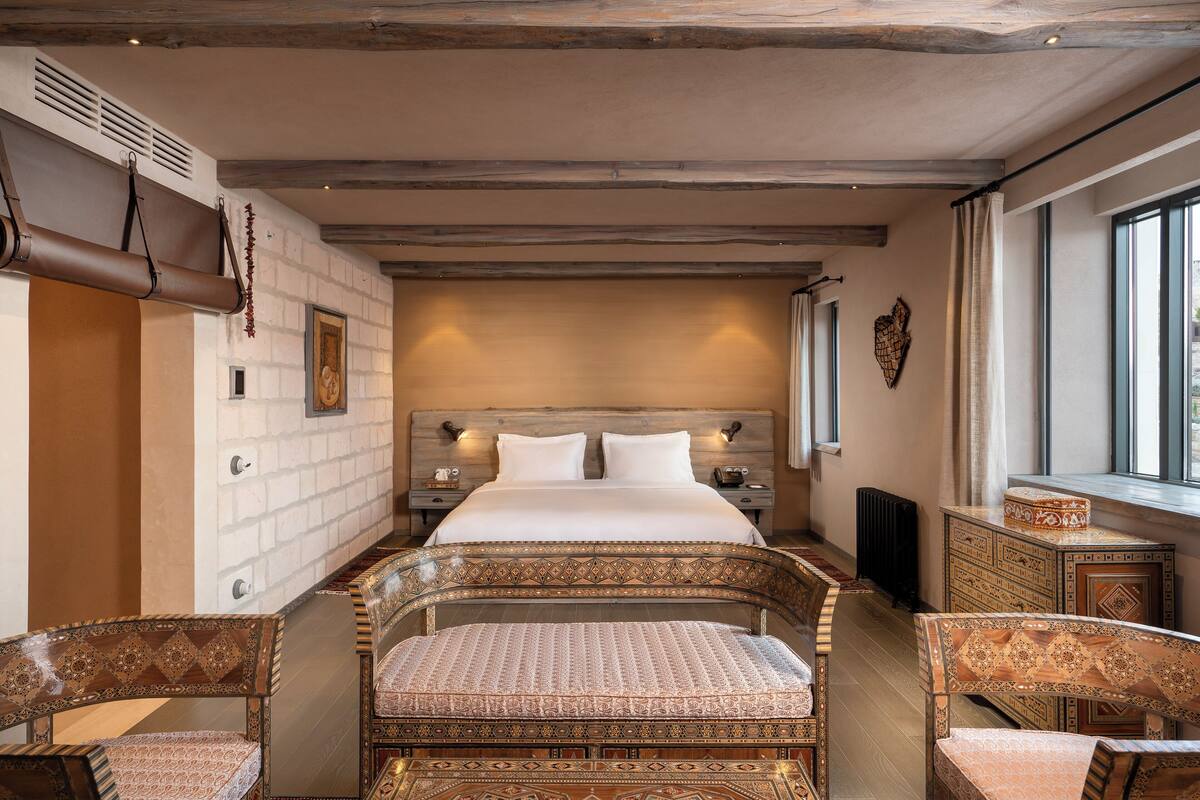 A hotel room with a large bed, two bedside tables, a chest of drawers, and a window.