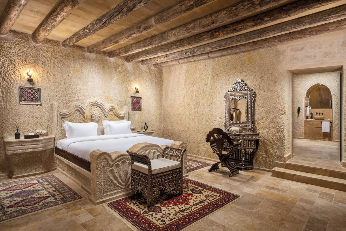 A traditional room with a large bed, a wooden chair, a mirror, and a rug.