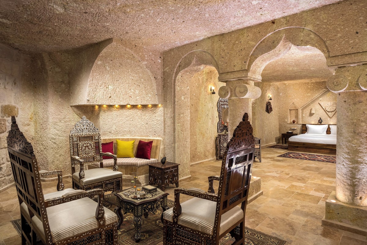 A luxurious room with ornate wooden furniture, a plush sofa, and a large bed.