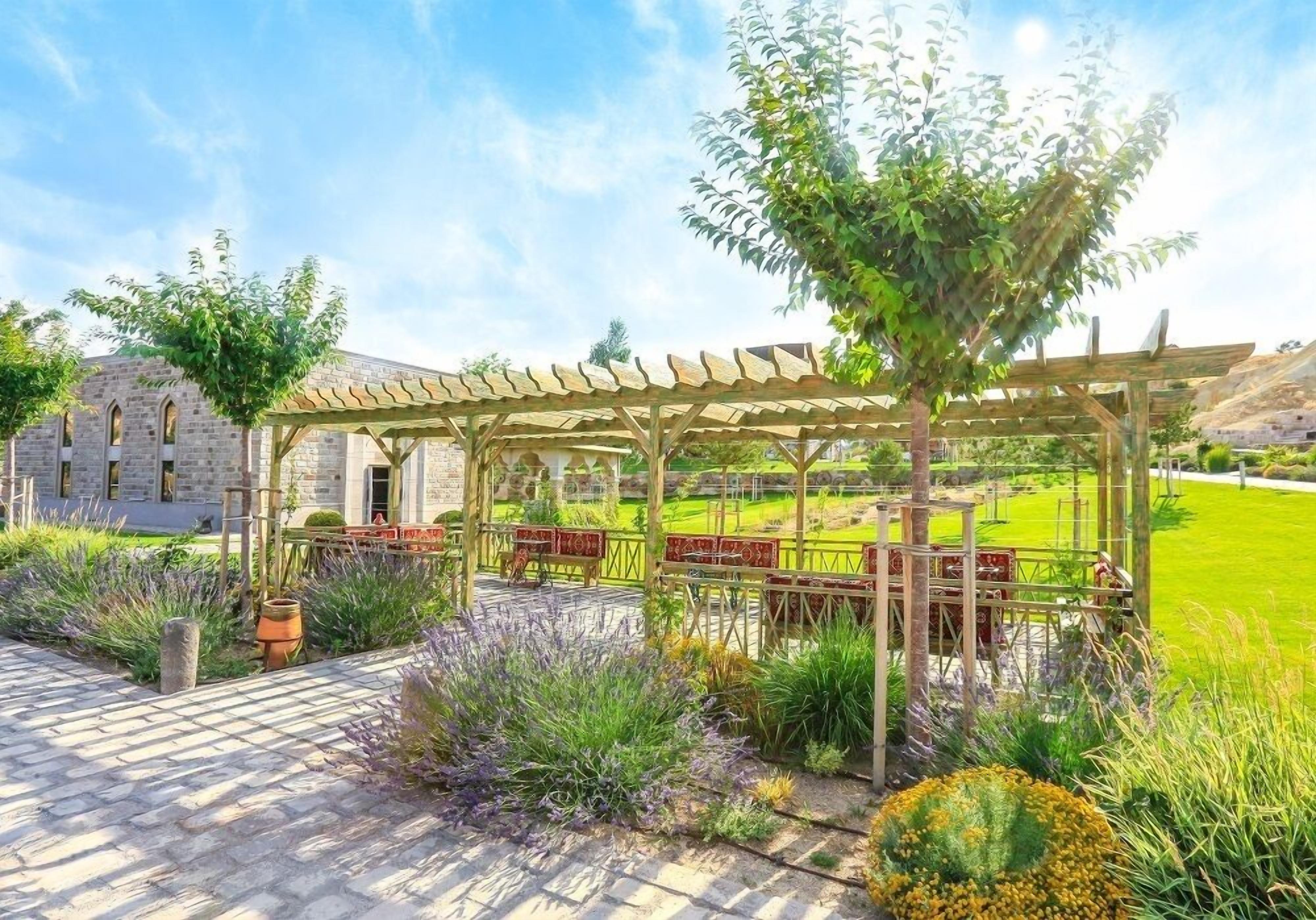 A garden with a pergola, stone building, and well-maintained lawn.