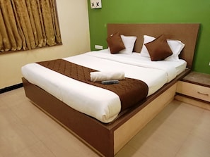 A neatly made bed with a brown headboard, white bedding, and a remote control on the bed. - Anmols impex cottage (Ootacamund)