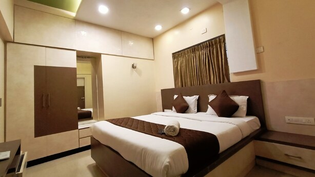 A modern hotel room with a large bed, a wardrobe, a desk, and a mirror. - Anmols impex cottage (Ootacamund)