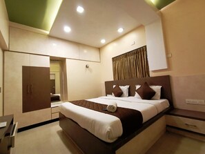 Una habitación de hotel moderna con una cama grande, un armario, un escritorio y un espejo.