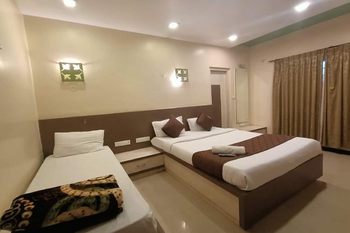 Una habitación de hotel con una cama grande, una cama más pequeña, un escritorio y un espejo.