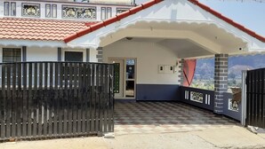 A house with a gated entrance, a tiled porch, and a view of the landscape. - Anmols impex cottage (Ootacamund)