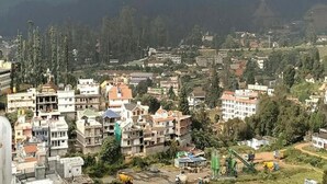 A residential area with multi-story buildings, some with balconies, and a mix of construction and undeveloped land. - Anmols impex cottage (Ootacamund)