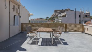 Une terrasse sur le toit, avec une table et des chaises, d’où l’on peut admirer un ancien fort et, au loin, des bâtiments modernes.