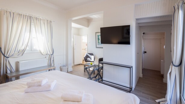 Une chambre d’hôtel avec un grand lit, un téléviseur fixé au mur, un bureau et une chaise.