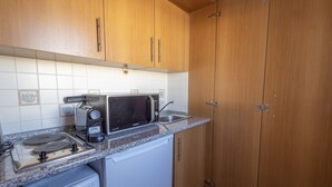 Une cuisine compacte dotée de meubles en bois, d’un four à micro-ondes, d’une machine à café et d’un lave-vaisselle.