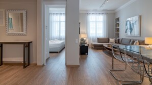 Una sala moderna con una mesa de vidrio, un sofá y una cama en la habitación contigua.