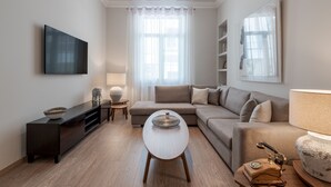 Una sala de estar moderna con un sofá, una mesa de centro, un televisor y una lámpara.