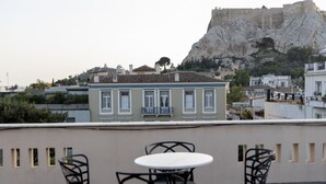 Una terraza con mesa y sillas, con vistas a un edificio histórico y una colina rocosa.