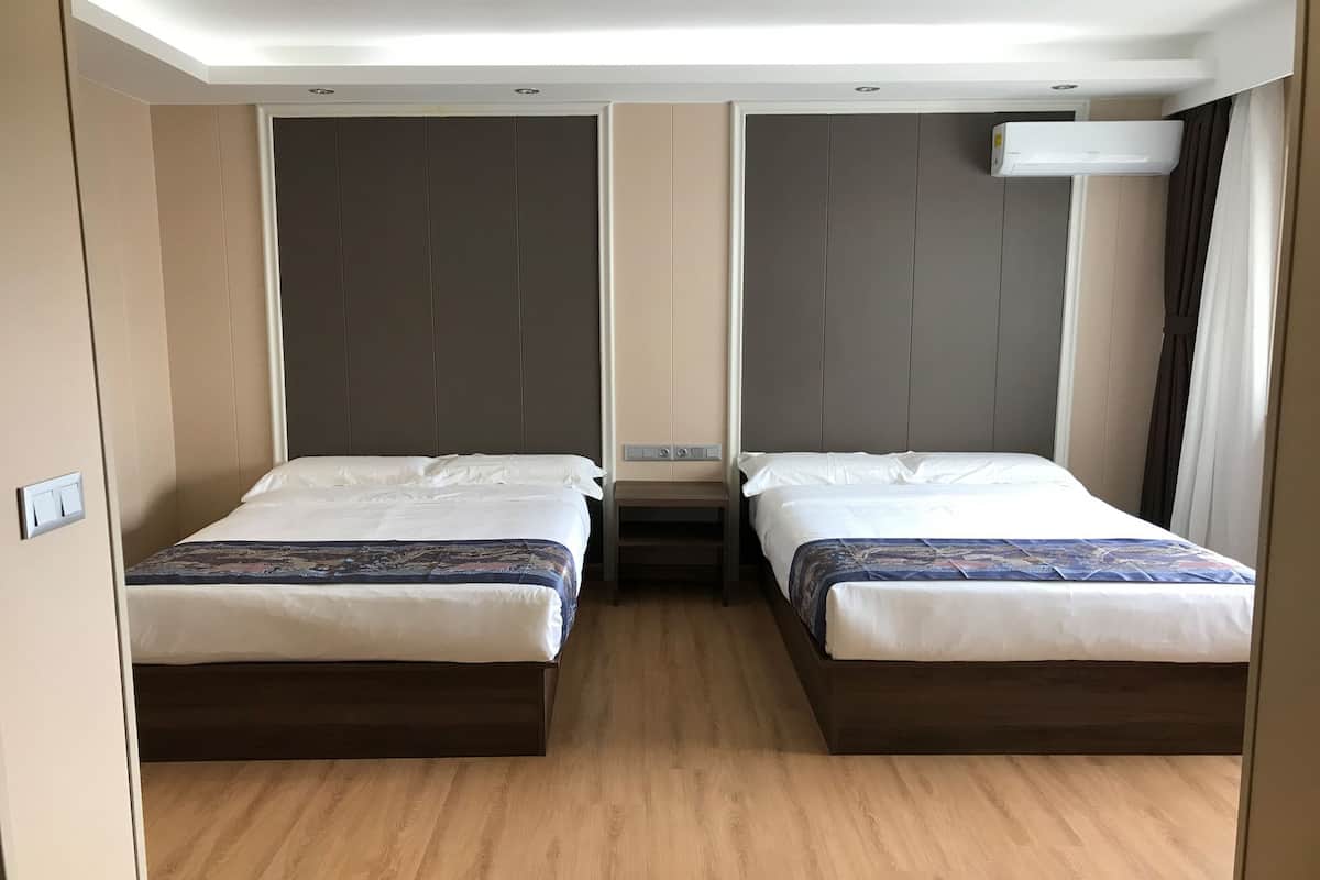Une chambre d’hôtel avec deux lits, une petite table, un appareil de climatisation et un interrupteur.