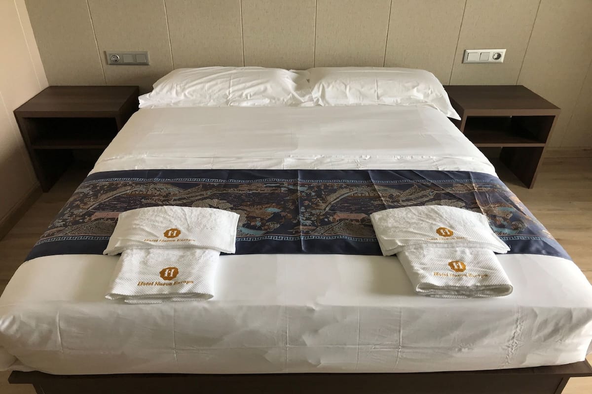 Une chambre d’hôtel avec un grand lit, deux tables de chevet et une couvre-lit à motifs.