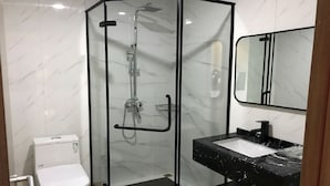 A modern bathroom with a glass-enclosed shower, a white toilet, and a black marble sink with a large mirror. - Hotel Nueva Europa (Torredembarra)