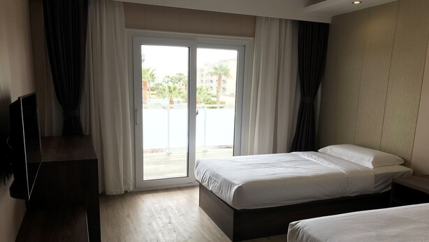 A hotel room with two beds, a desk, and a television. - Hotel Nueva Europa (Torredembarra)