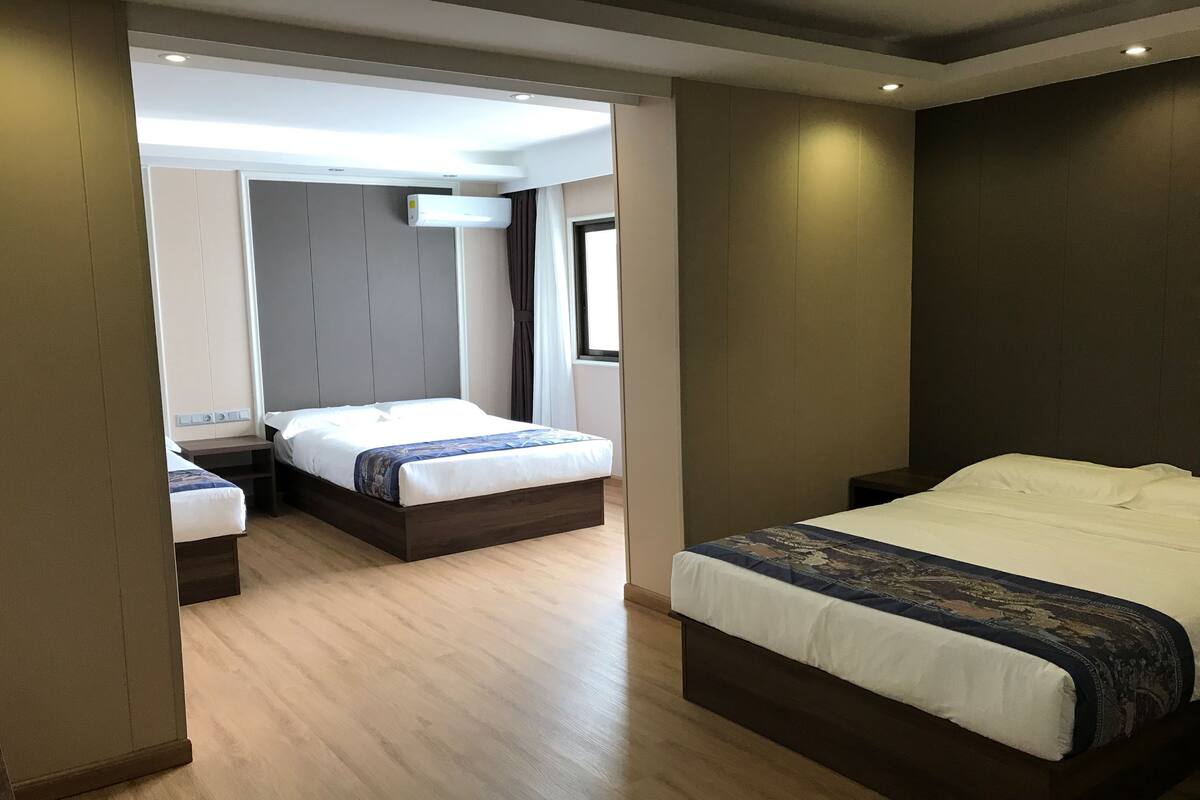 Une chambre d’hôtel avec deux lits, un climatiseur fixé au plafond et une fenêtre avec des rideaux.