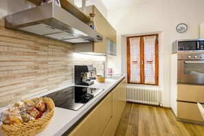 Eine moderne Küche mit Einbauherd, einer Kaffeemaschine und einem Fenster mit gemusterten Vorhängen.
