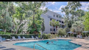 A swimming pool with lounge chairs and a building in the background. - Ocean breeze treetops 2 bdrm walk to beach tennis dog friendly w/d permit#070894 (Hilton Head Island)