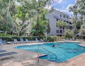 A swimming pool with lounge chairs and a building in the background.