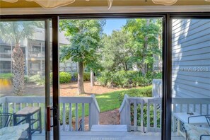 Vue depuis une pièce dont la porte-fenêtre donne sur une terrasse extérieure.