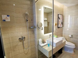 Une salle de bain moderne avec une douche à parois de verre, un lavabo avec un miroir et des toilettes.