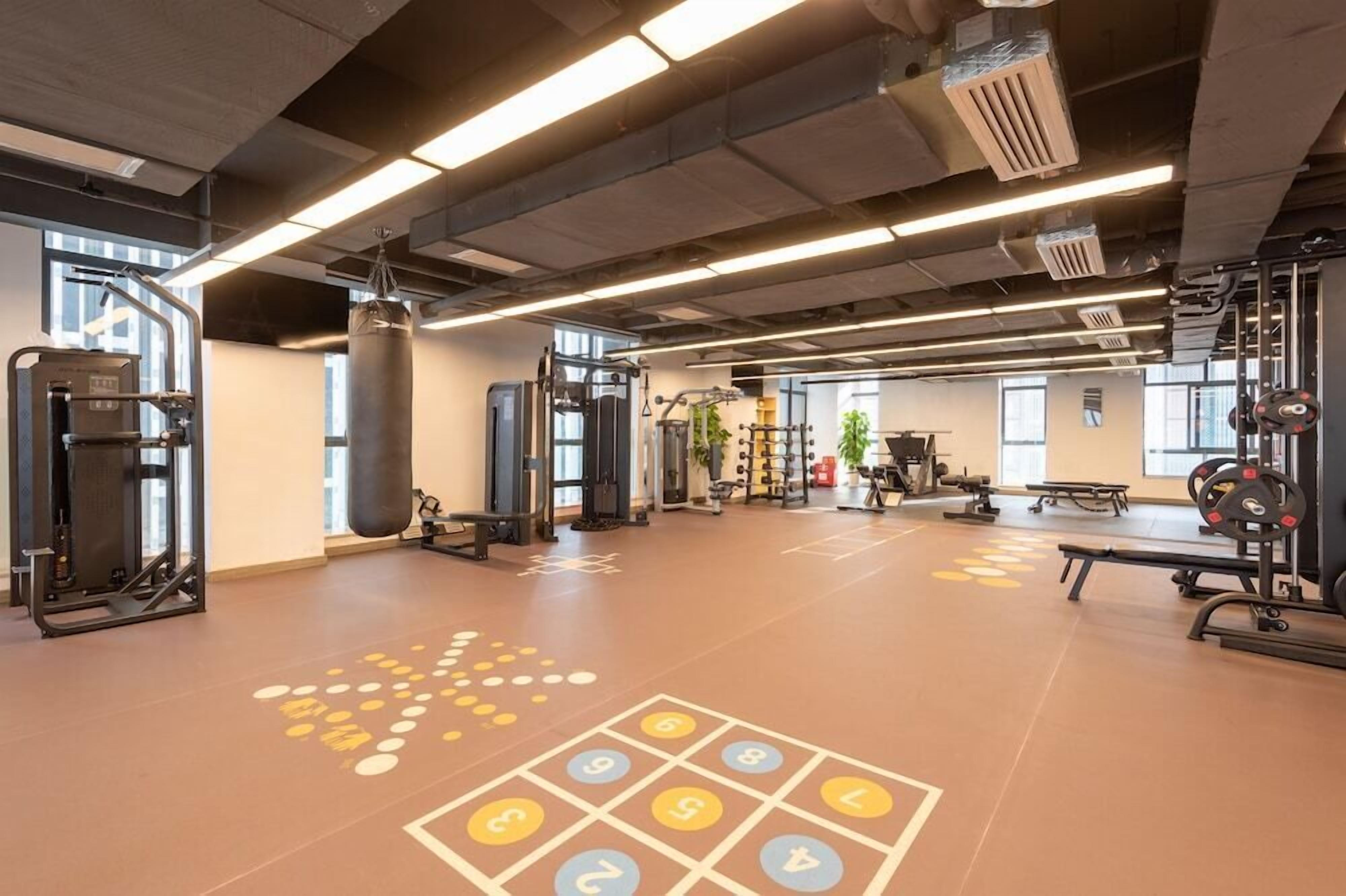 Un gimnasio con equipo de ejercicio, un saco de boxeo y un suelo con diseño de rayuela.