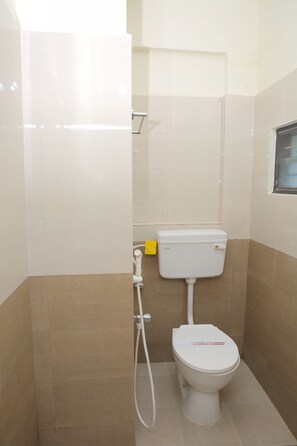 A small, clean bathroom with a toilet, a shower, and a window.