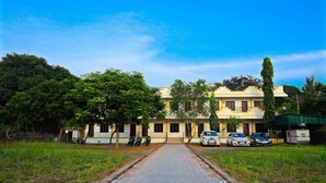 A building with a paved entrance, parked cars, and trees. - Rani Residency (Vanur)