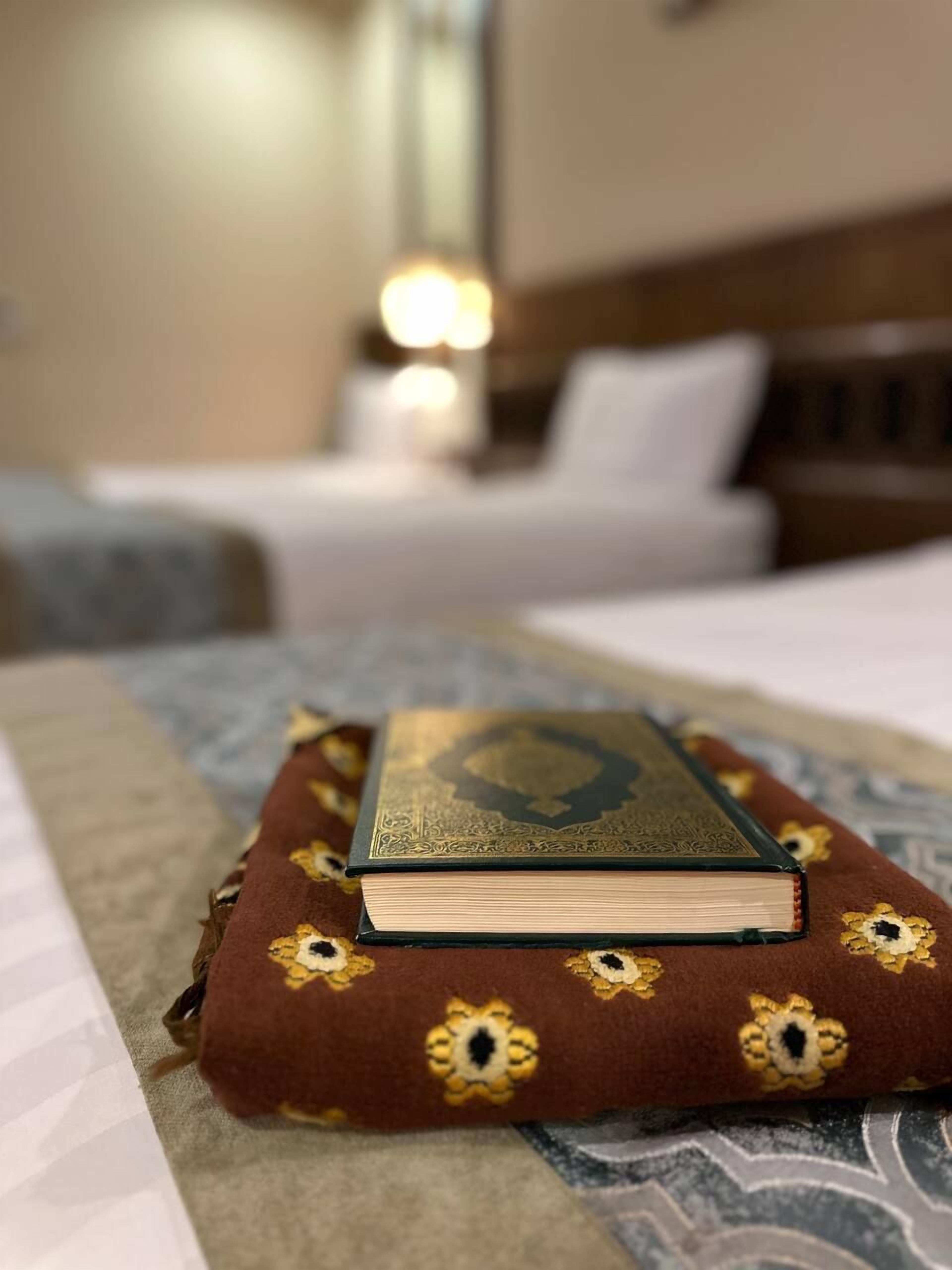 A bed with a pillow and a book on a patterned bedspread.