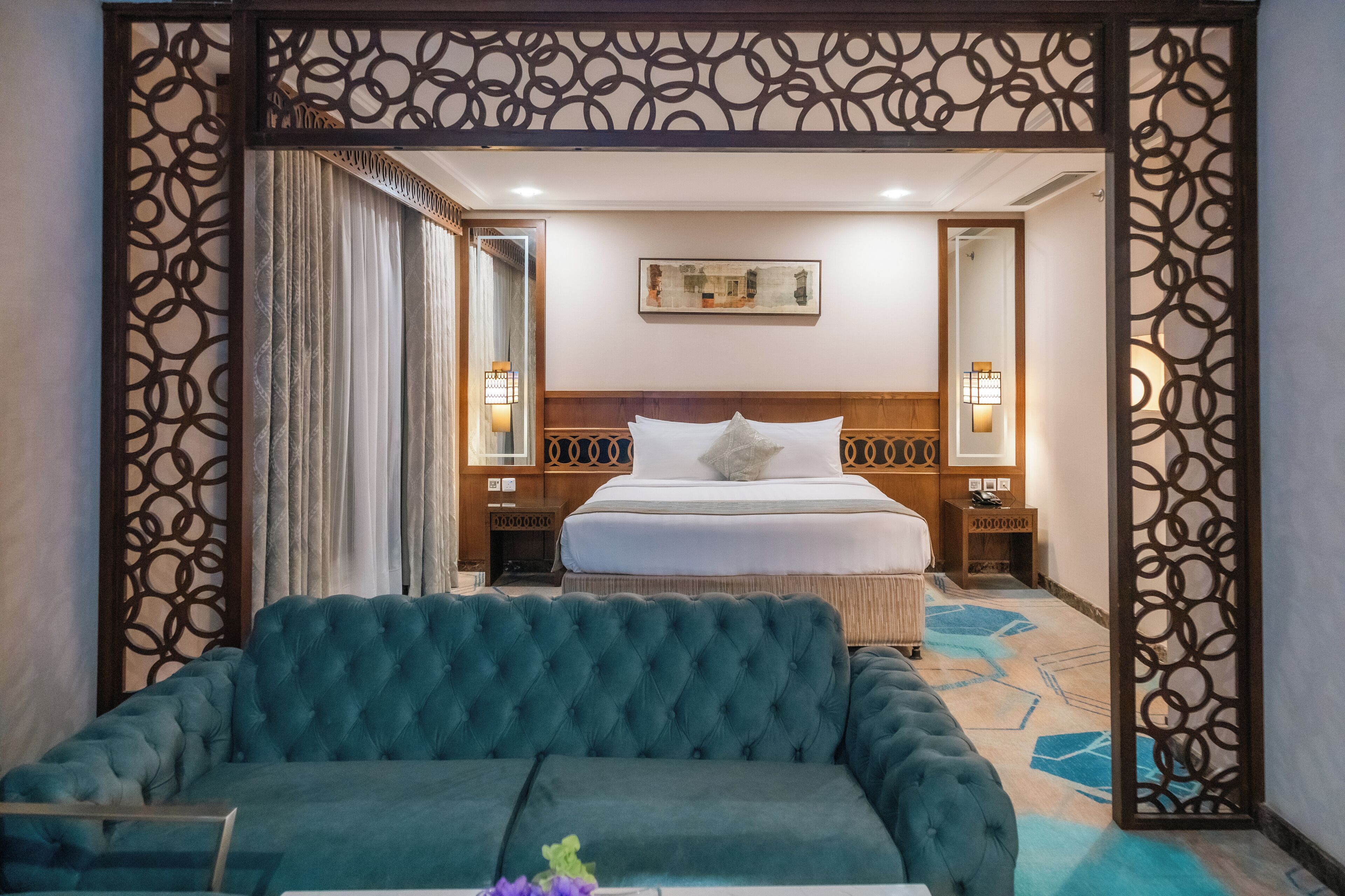 Une chambre d’hôtel avec un grand lit, un canapé et un paravent décoratif.