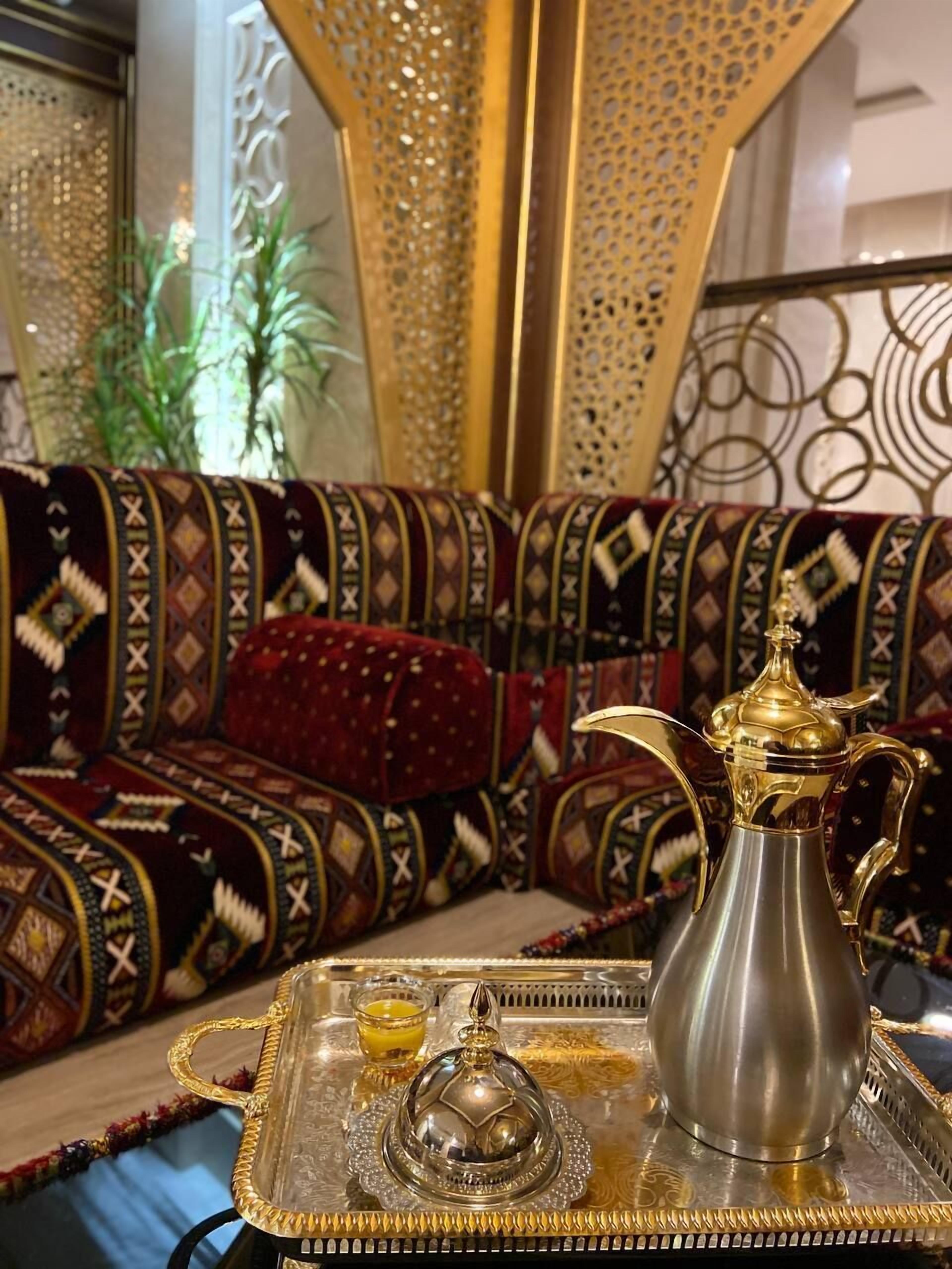 A traditional Moroccan interior with patterned sofas, a tray with a pitcher and teapot, and decorative elements.