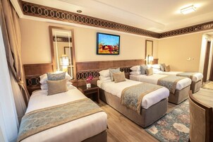 Habitación de hotel con tres camas, un espejo grande, un cuadro en la pared y cabecera de madera.