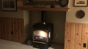 Ein Wohnzimmer mit Kaminofen, einer hölzernen Bank und einem an der Wand befestigten Regal mit Dekoration.