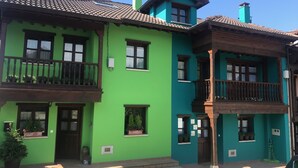 Un edifici de dues plantes amb façana verda, balcons de fusta i teulada enrajolada.