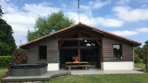 Eine Holzhütte mit Whirlpool, einer Sitzbank und einer Terrassenfläche.