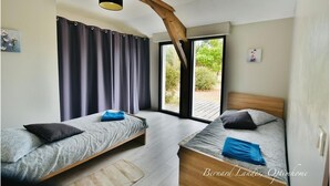 Ein Schlafzimmer mit zwei Betten, einem großen Fenster und einem Holzbalken an der Decke.