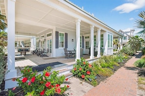 A covered outdoor area with a patio, seating, and a pathway with flowers.