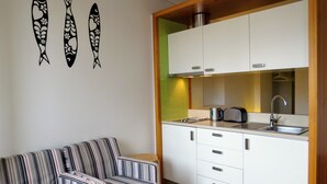 Una cucina compatta con mobili bianchi, un lavandino e un divano a righe.