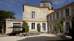 A courtyard with outdoor seating and a building with a corner tower.