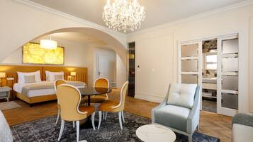 Una habitación de hotel con una cama, una zona de comedor con sillas, un candelabro y un armario con puertas correderas.