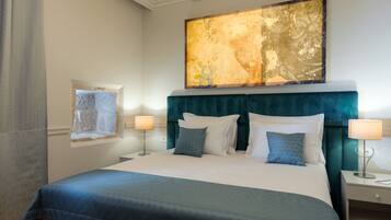Une chambre d’hôtel avec un grand lit, deux tables de chevet, une commode, une fenêtre avec vue et un grand tableau abstrait accroché au mur.