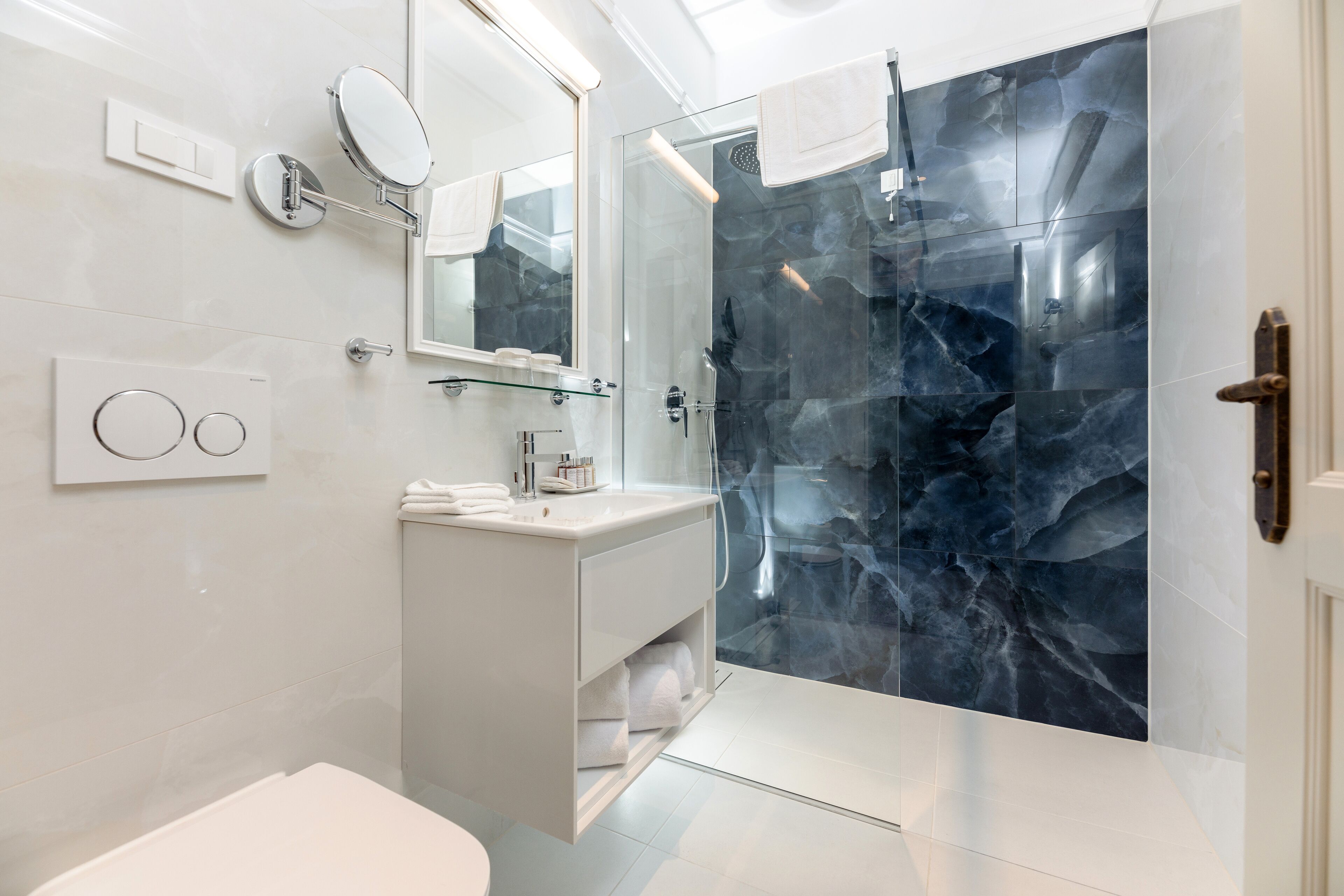 Une salle de bain moderne avec une douche à parois de verre, un meuble-lavabo blanc et un grand miroir.