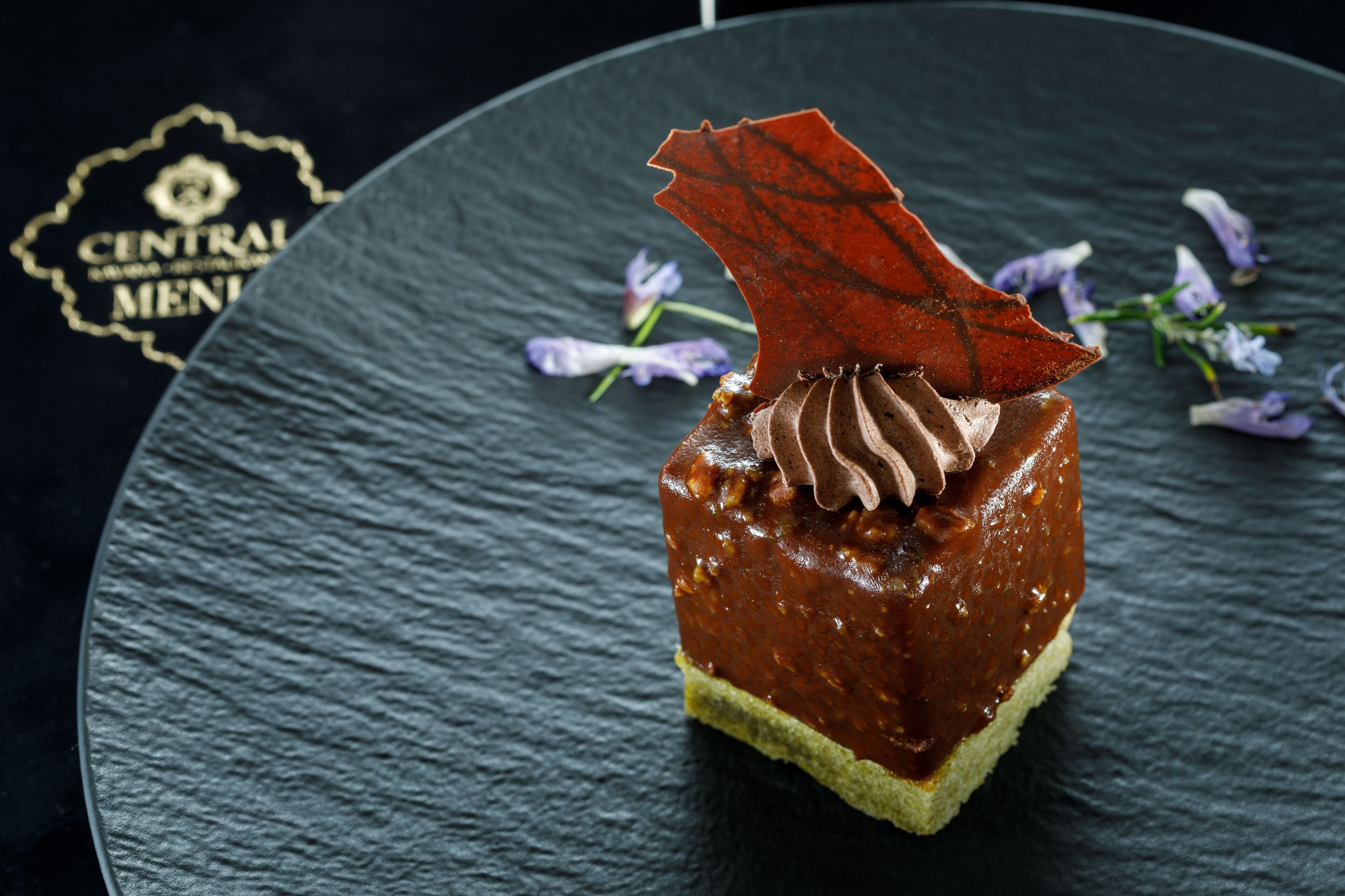 Un postre sobre un plato de pizarra con fondo oscuro.