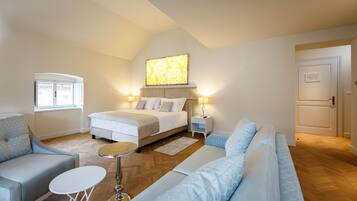 A modern bedroom with a large bed, bedside tables, a sofa, and a small round table.
