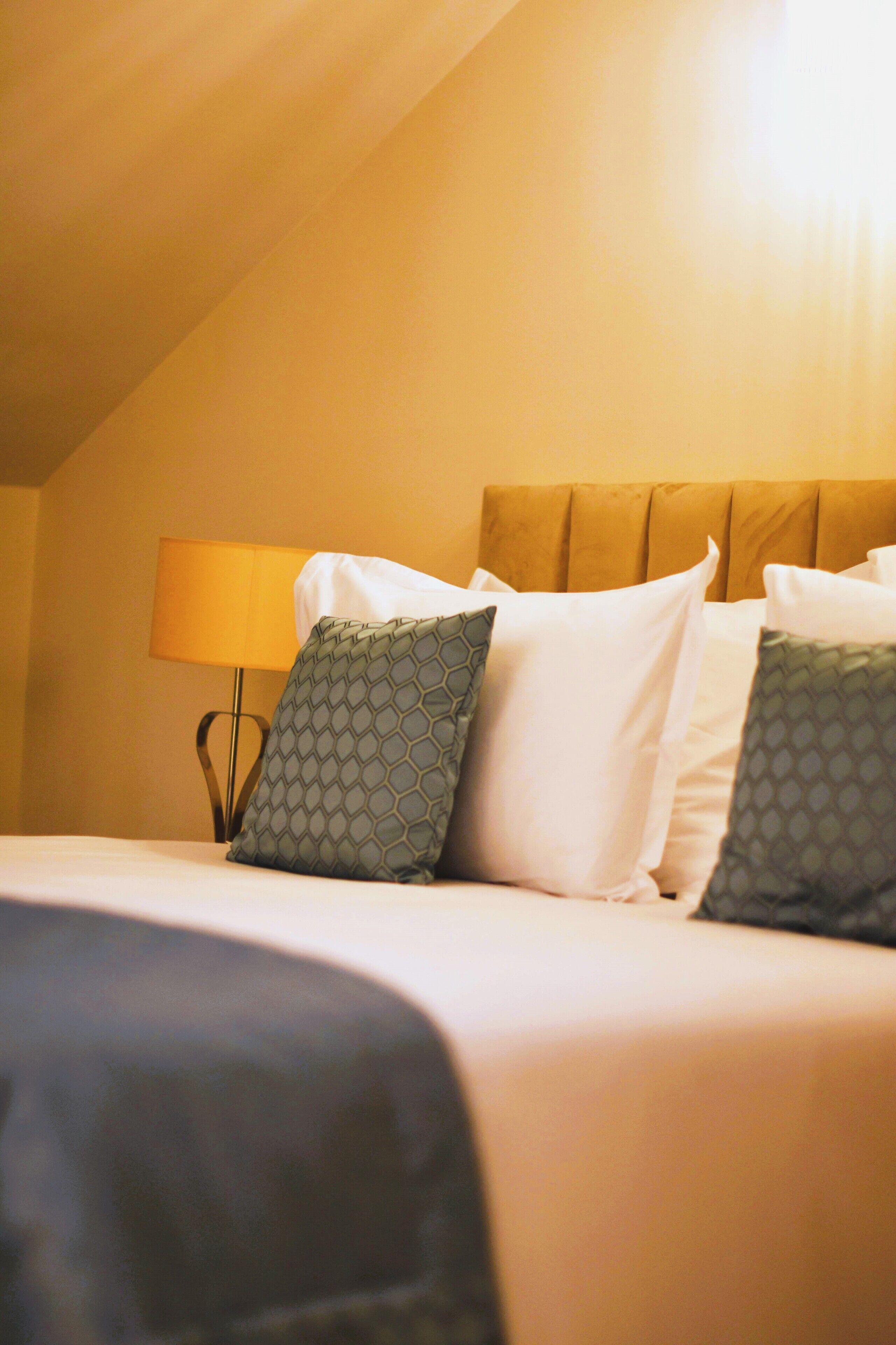 Ein Hotelzimmer mit Bett, Kissen, Lampe und Kopfteil.