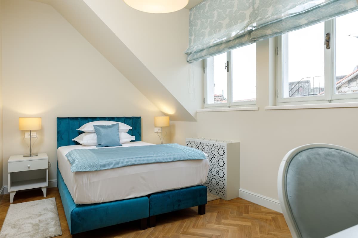 A bedroom with a bed, bedside tables, a chair, and a window with a view.