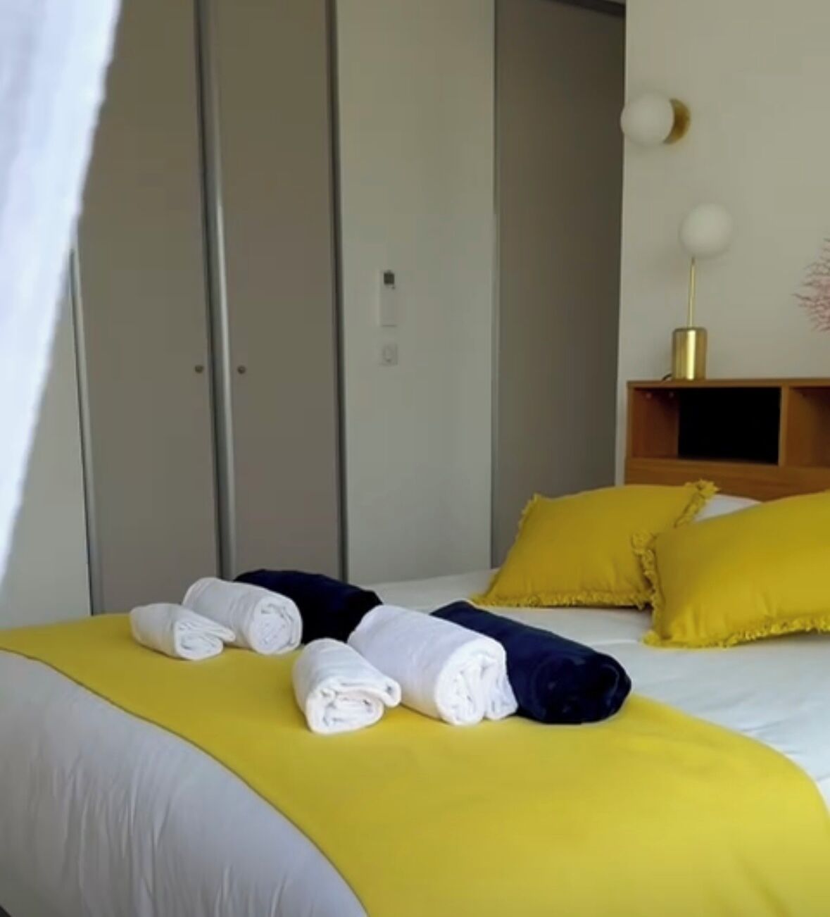 Une chambre d’hôtel avec un lit, des oreillers jaunes et des serviettes enroulées.