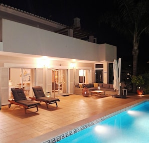 Un área junto a la piscina con sillones, un sofá y una mesita.
